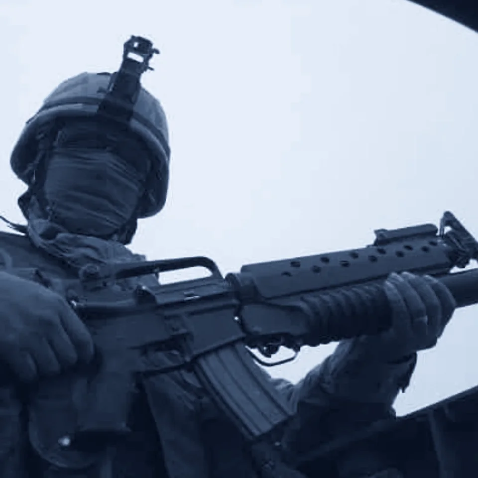 Ferdinand Orbino in uniform during his military service, wearing a helmet and face wrap and holding a rifle
